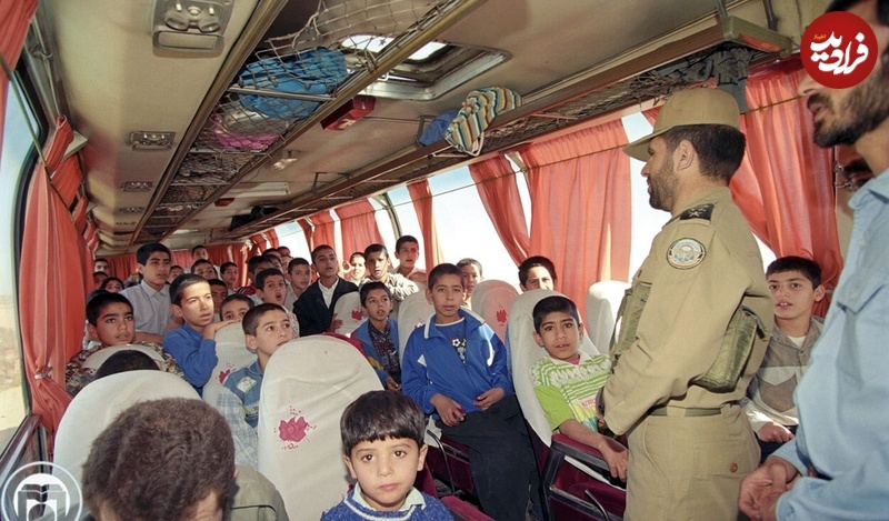 no-name-103 عکس؛ سفر به تاریخ؛ «سپهبد صیاد شیرازی» در حال سخنرانی برای کودکان در اتوبوس؛ دهۀ 70